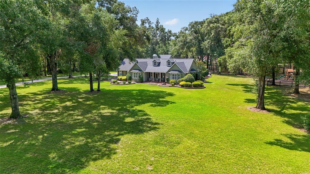 An aerial view of a green house with a gray roof set on a large lawn — 7040 SW 97TH PLACE, OCALA, FL
