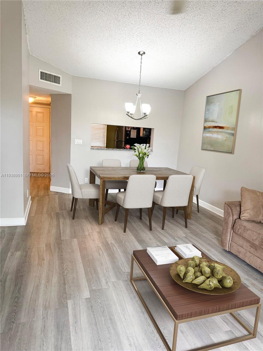 A dining area with a wooden table and chairs sits adjacent to a living room — 5580 Lakeside Dr # 205, Margate FL 33063, MARGATE, FL