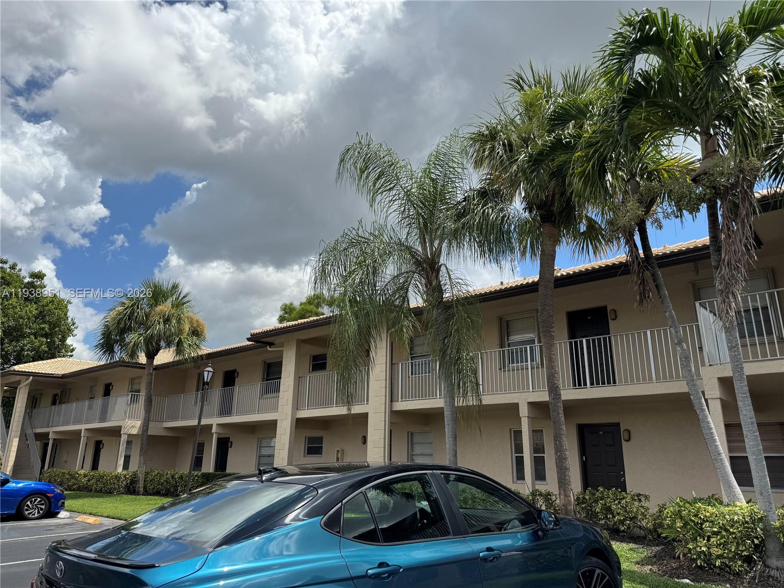 A two-story apartment building with beige stucco walls and palm trees in front — 5580 Lakeside Dr # 205, Margate FL 33063, MARGATE, FL