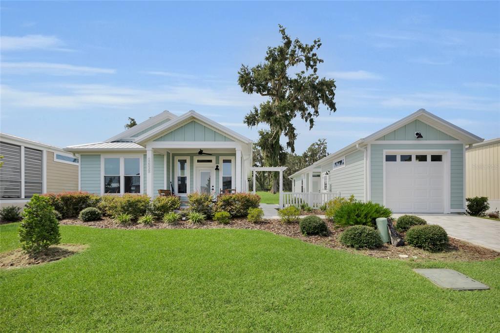 A light green house with a front porch and a detached garage on a lawn — 12039 LAKESHORE WAY, OXFORD, FL