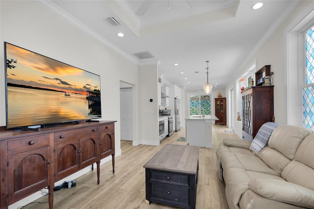 A living room with a television, wooden console, coffee table, and sofa leads to a kitchen — 12039 LAKESHORE WAY, OXFORD, FL