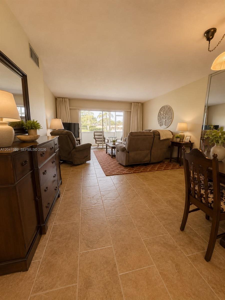 A living room features tile flooring, a brown sofa, and a sliding glass door — 20 Abbey Ln # 101, Delray Beach FL 33446, DELRAY BEACH, FL