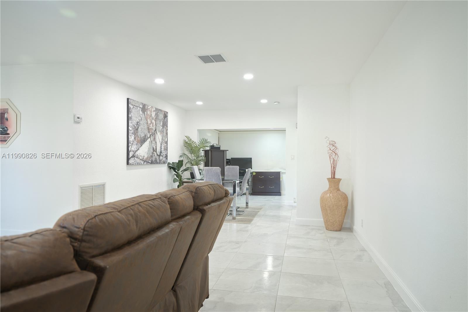 A living room with white walls and tile flooring leads into a dining area — 4391 NW 12th Ter, Deerfield Beach FL 33064, DEERFIELD BEACH, FL