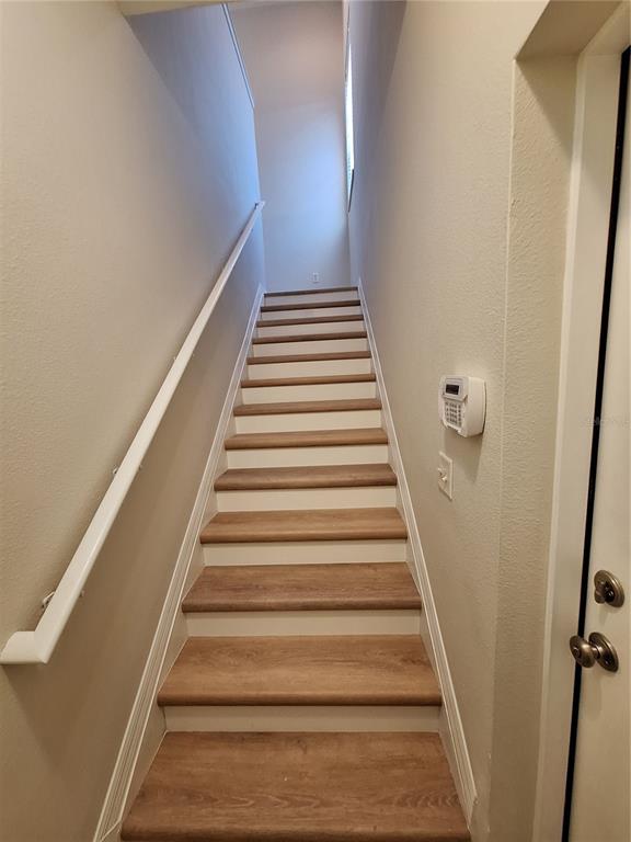A staircase with wood-look treads and white risers leads upward between two beige walls — 3709 PARKRIDGE CIRCLE UNIT 7-204, SARASOTA, FL
