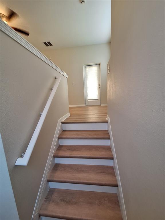 A staircase with wood-look treads and white risers leads to a landing with a door — 3709 PARKRIDGE CIRCLE UNIT 7-204, SARASOTA, FL