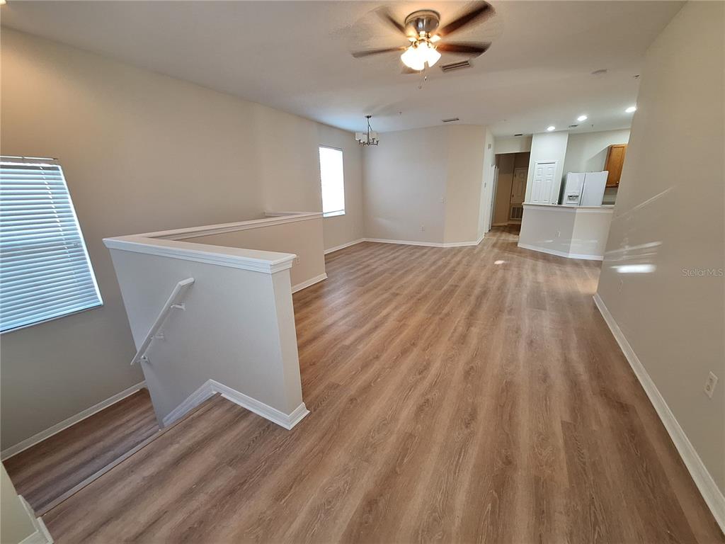 An open-concept living area features light wood-look flooring, a ceiling fan, and a staircase — 3709 PARKRIDGE CIRCLE UNIT 7-204, SARASOTA, FL