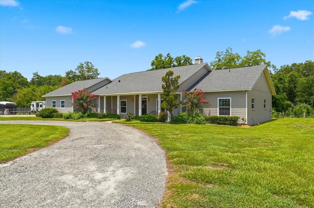 A single-story house with light gray siding and a gravel driveway sits on a lawn — 8404 MATHEWS ROAD, LAKELAND, FL