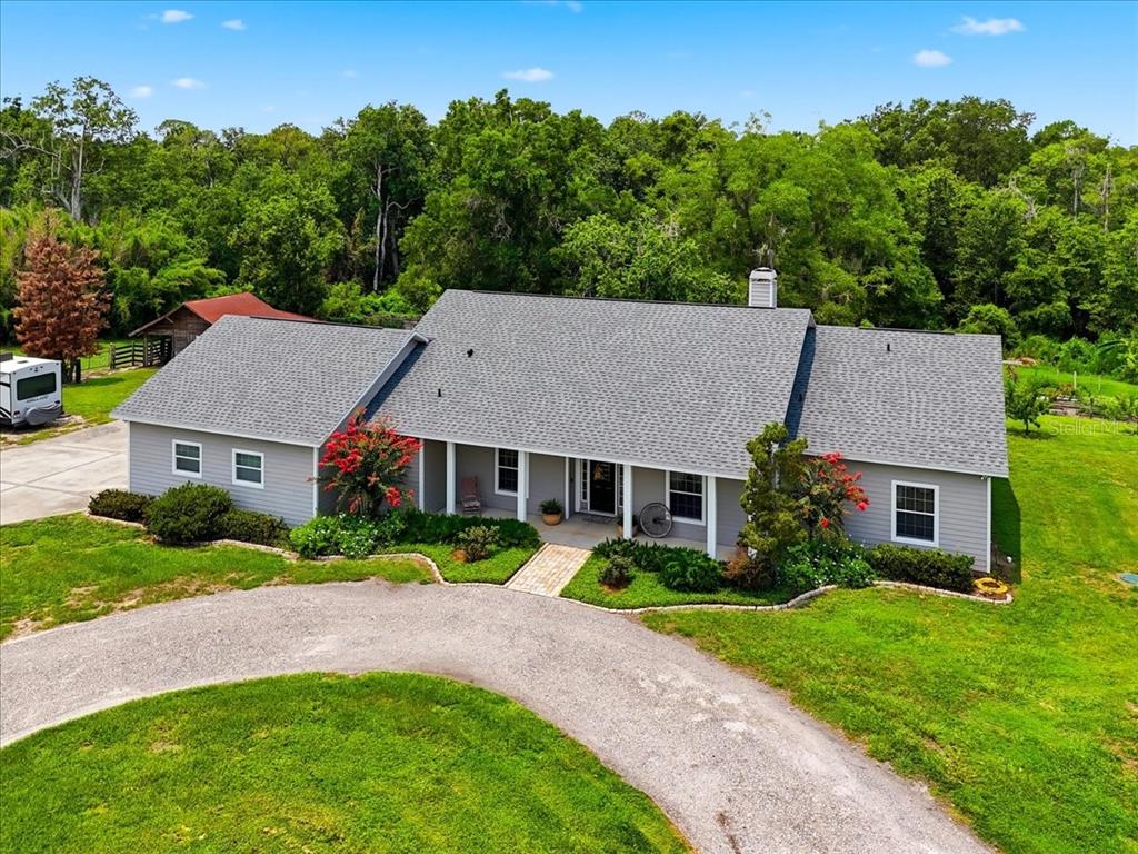 An aerial view of a gray, single-story ranch-style house with a gravel driveway and lawn — 8404 MATHEWS ROAD, LAKELAND, FL