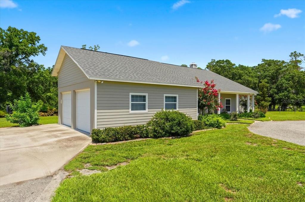A light-colored house with a two-car garage and a covered porch sits on a lawn — 8404 MATHEWS ROAD, LAKELAND, FL