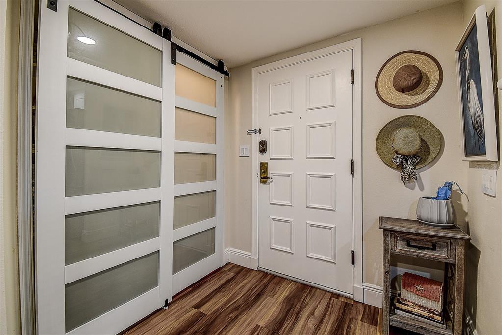 An entryway features a white sliding barn door, a white front door, and a wooden console table — 36750 US HIGHWAY 19 UNIT 24-213, PALM HARBOR, FL