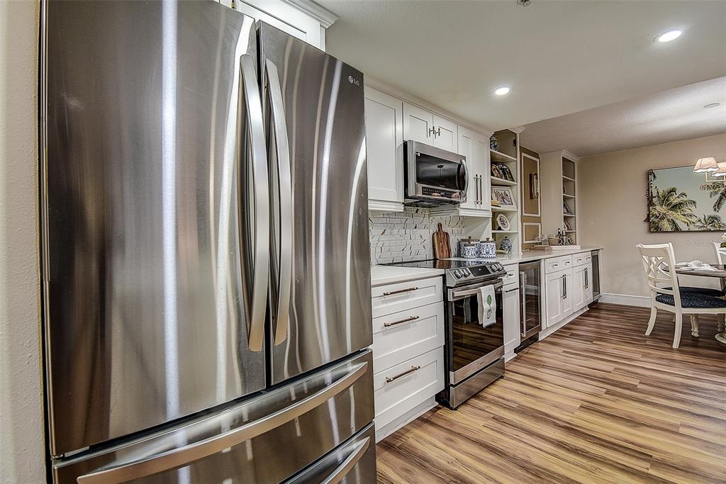 A kitchen with stainless steel appliances, white cabinets, and wood-look flooring — 36750 US HIGHWAY 19 UNIT 24-213, PALM HARBOR, FL