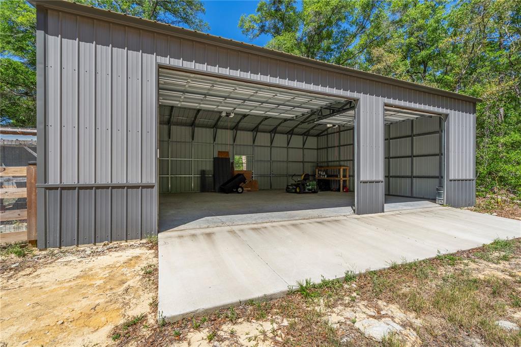 A gray metal garage with two open bays and a concrete driveway — 1886 STATE ROAD 20, HAWTHORNE, FL