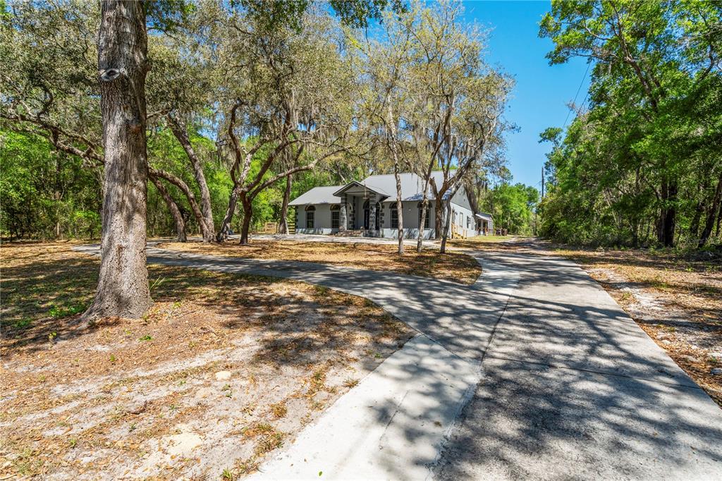 A gray house with a metal roof sits at the end of a concrete driveway — 1886 STATE ROAD 20, HAWTHORNE, FL