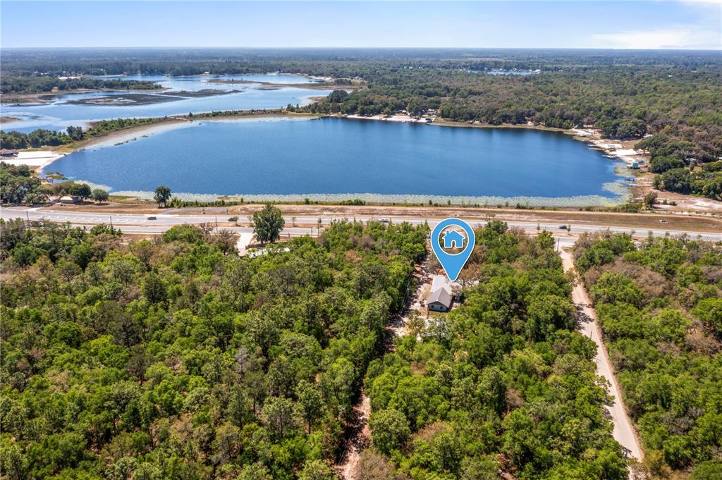 An aerial view shows a house nestled in a wooded area near a large lake — 1886 STATE ROAD 20, HAWTHORNE, FL
