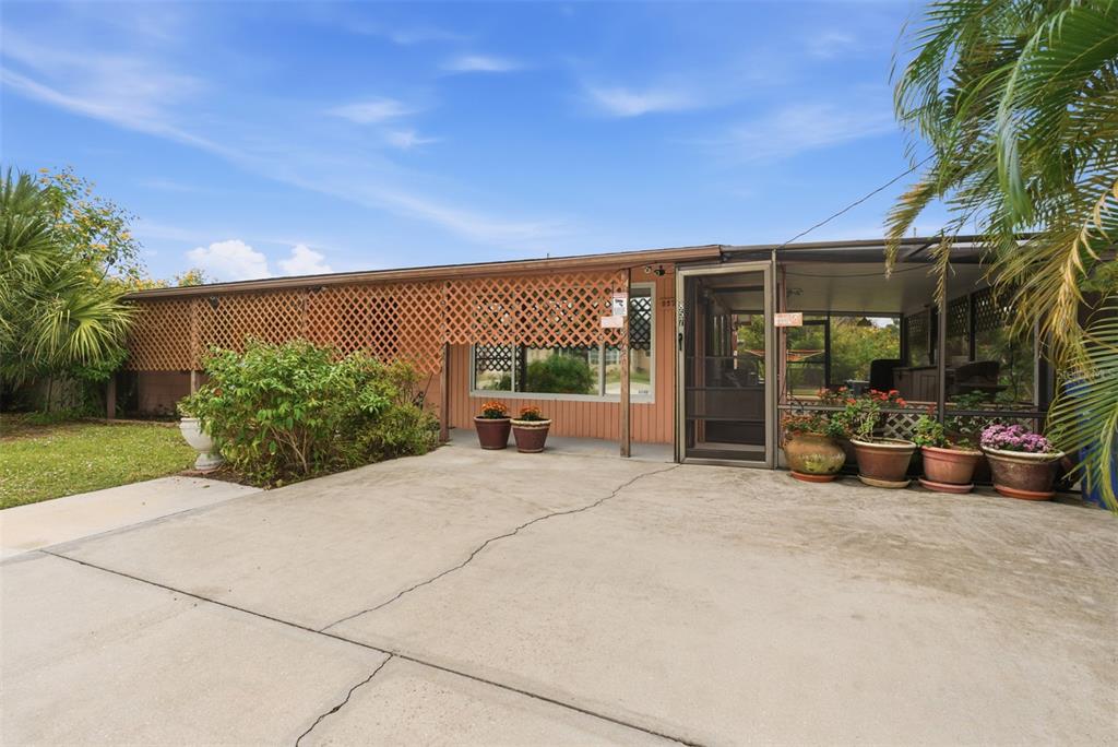 A single-story house with a concrete driveway, lattice privacy screen, and a screened-in porch — 857 PALMETTO STREET, ENGLEWOOD, FL