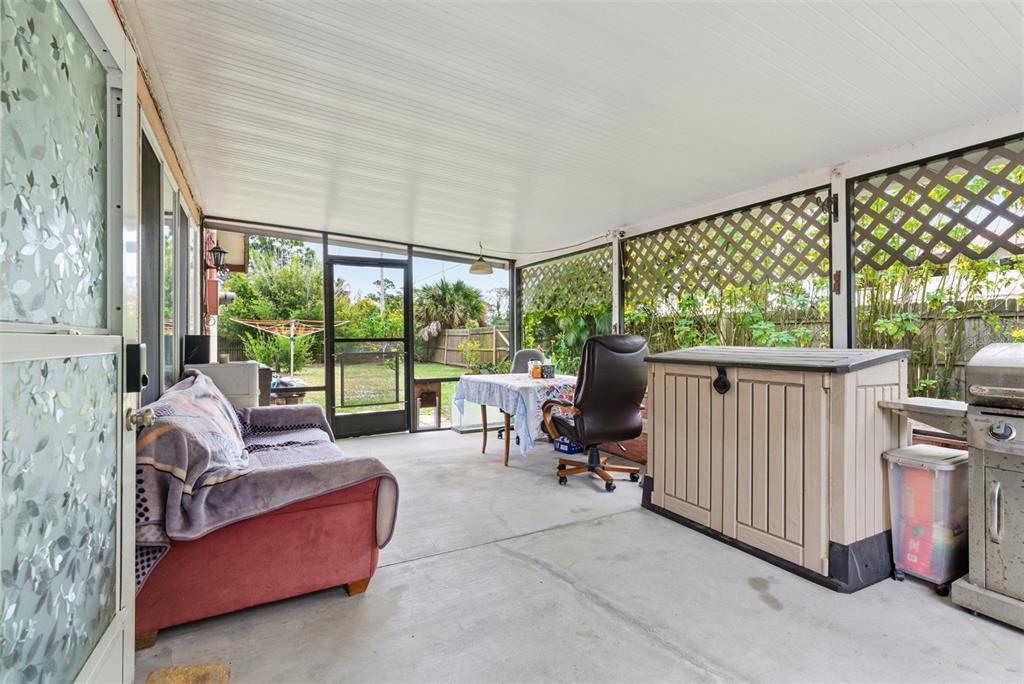 A screened-in patio features a concrete floor, a sofa, a dining table, and outdoor storage — 857 PALMETTO STREET, ENGLEWOOD, FL