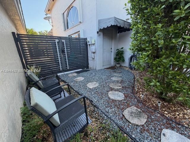 A small patio with gravel, stone pavers, two chairs, and a black privacy fence — 8277 NW 194th Ter # 2, Hialeah FL 33015, HIALEAH, FL
