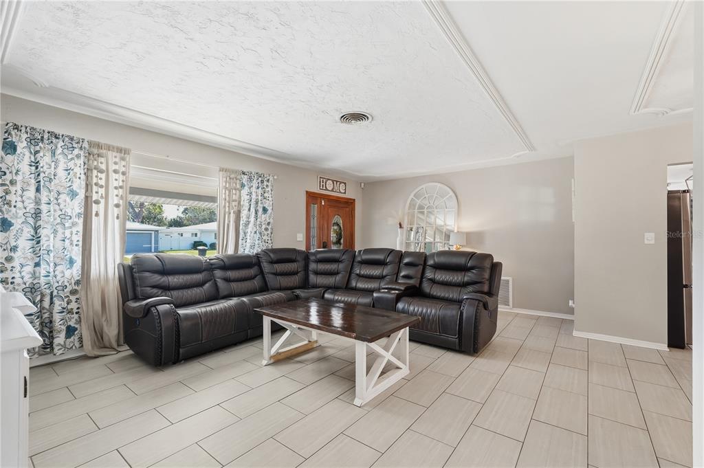 A living room features a large dark leather sectional, a coffee table, and tiled floors — 2701 64TH AVENUE S, ST PETERSBURG, FL