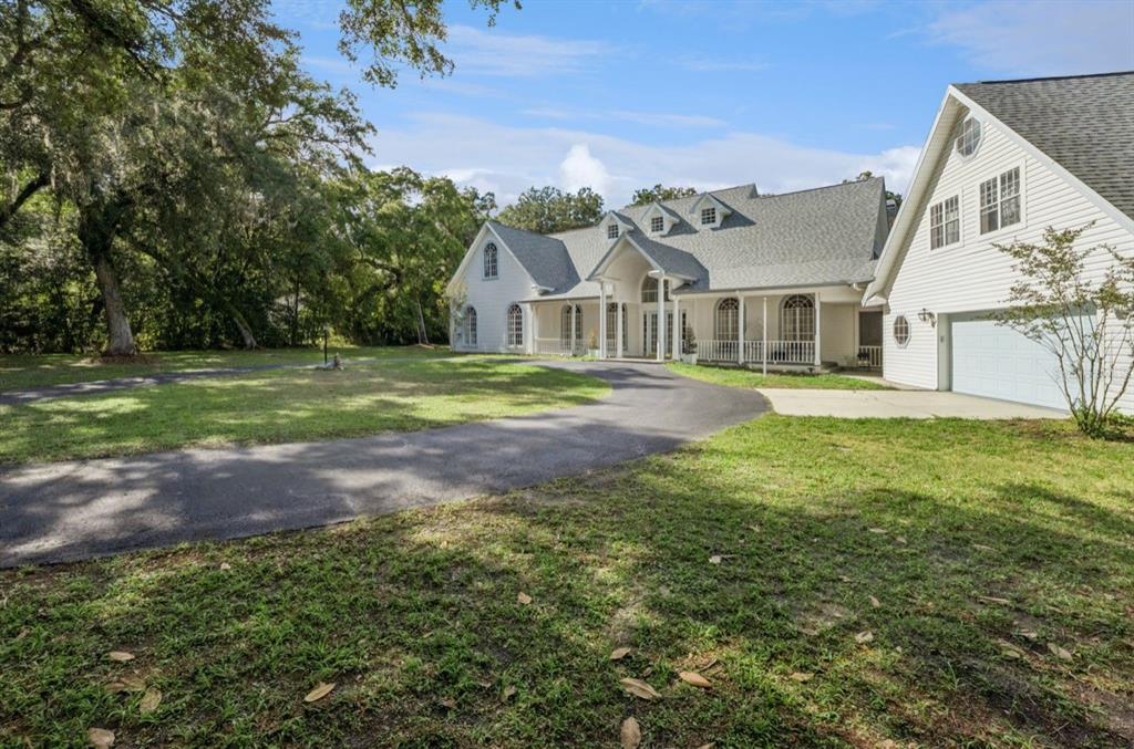 A large white two-story house with a circular driveway and a detached garage — 21033 VIOLET ROAD, BROOKSVILLE, FL