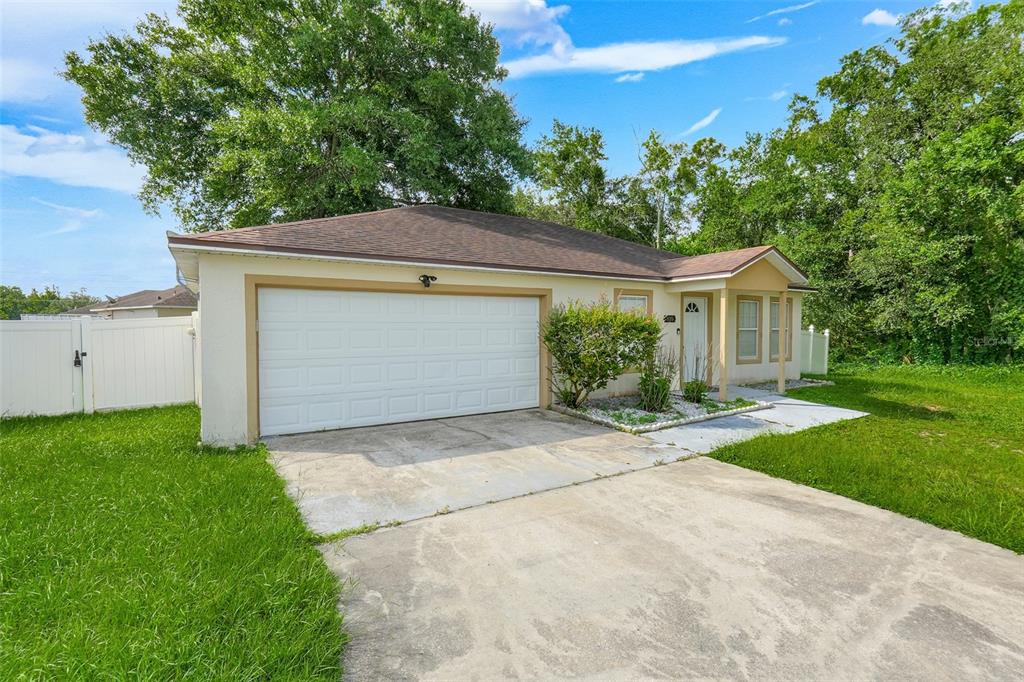 A single-story house with a white garage door, beige siding, and a concrete driveway — 810 VALNERA COURT, KISSIMMEE, FL