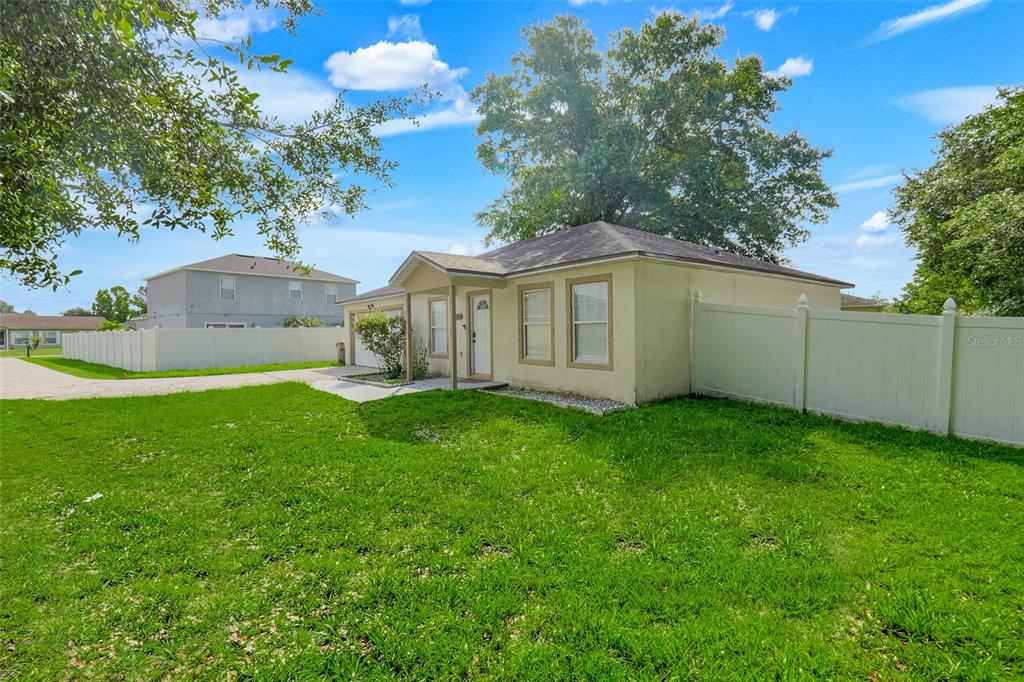 A single-story house with a white vinyl fence and a large tree in the yard — 810 VALNERA COURT, KISSIMMEE, FL