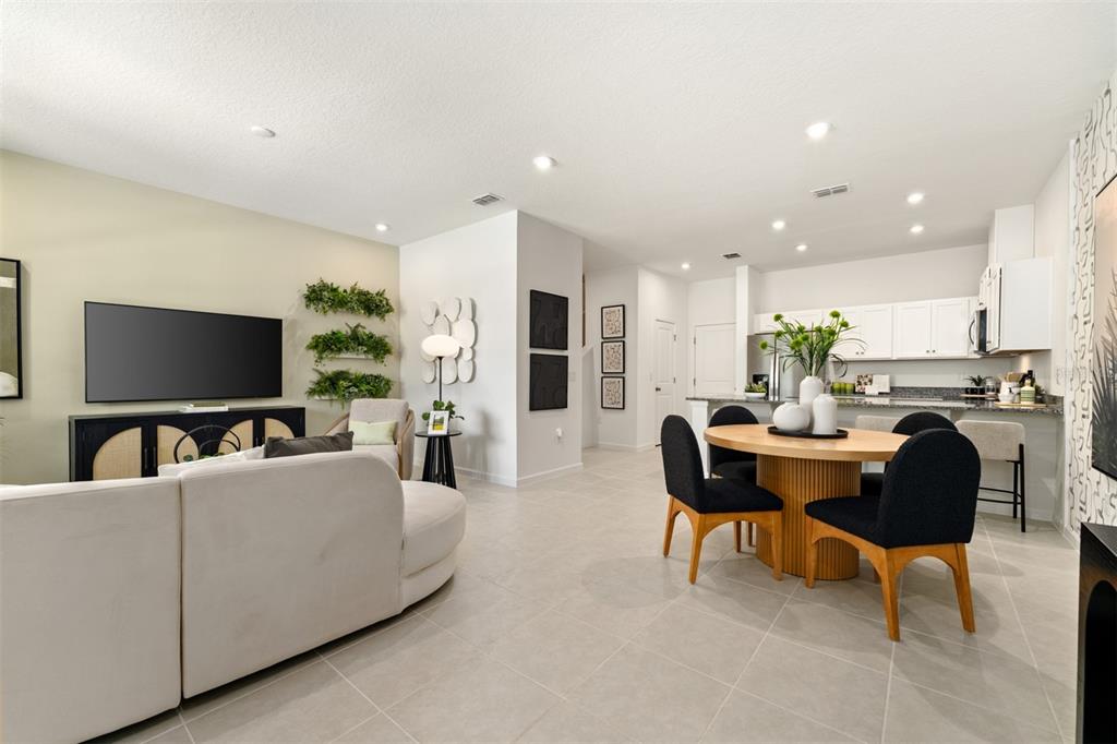An open-concept living and dining area features a white sofa, round table, and modern decor — 160 RAINWOOD STREET, GROVELAND, FL