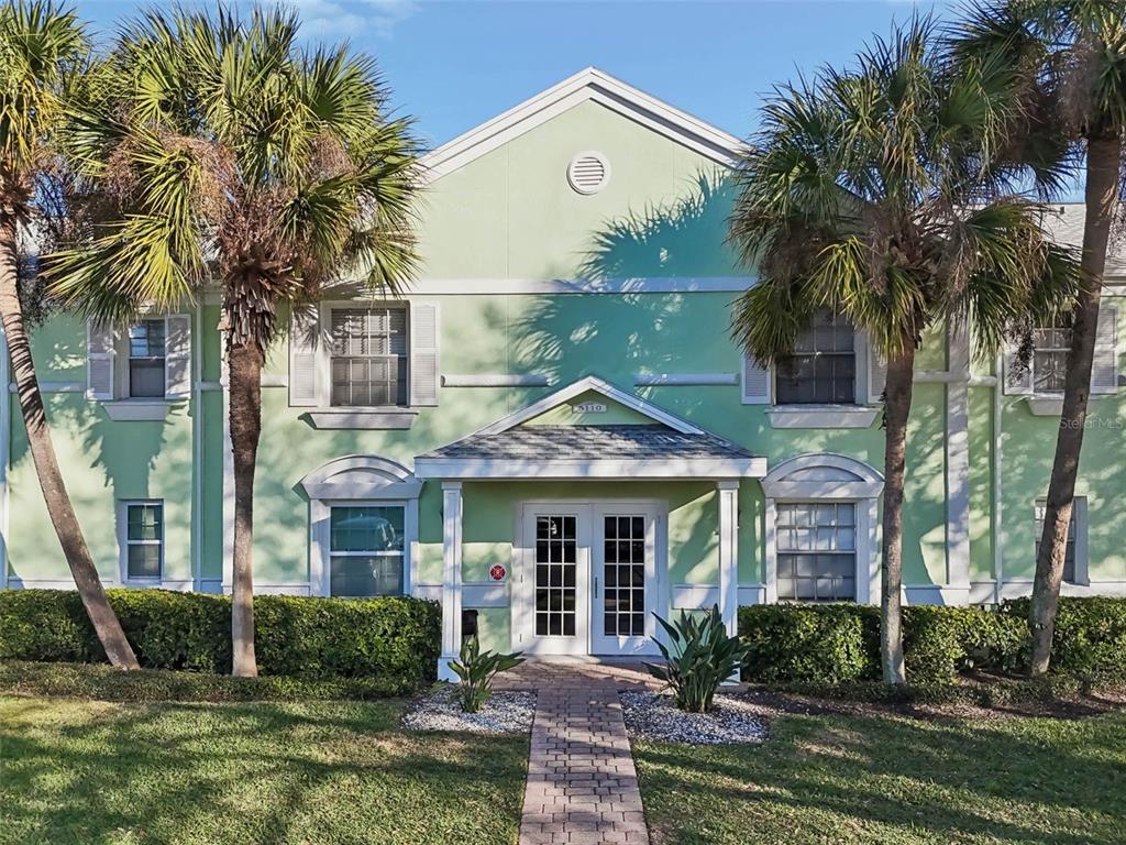 A two-story light green building with a central entrance and palm trees in front — 5110 COQUINA KEY DRIVE SE UNIT C, ST PETERSBURG, FL