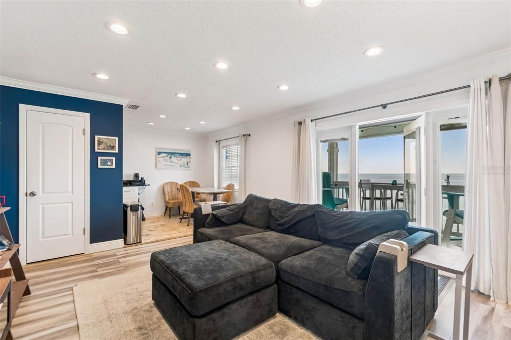 A living room with a dark sectional sofa, blue accent wall, and a balcony view — 5110 COQUINA KEY DRIVE SE UNIT C, ST PETERSBURG, FL