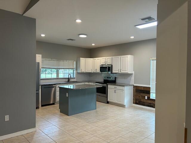 A kitchen features white cabinets, a blue island, stainless steel appliances, and tile flooring — 1301 SW 83rd Avenue, Okeechobee FL 34974, OKEECHOBEE, FL