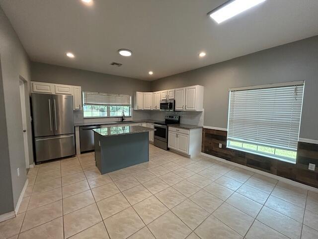 A kitchen features white cabinets, stainless steel appliances, a gray island, and tile flooring — 1301 SW 83rd Avenue, Okeechobee FL 34974, OKEECHOBEE, FL