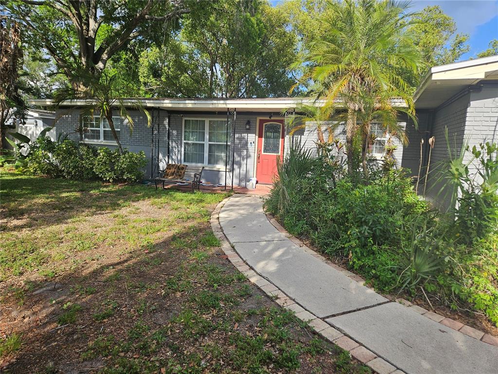 A single-story gray brick house features a red front door and a curved concrete walkway — 347 COUNTRY CLUB DRIVE, OLDSMAR, FL