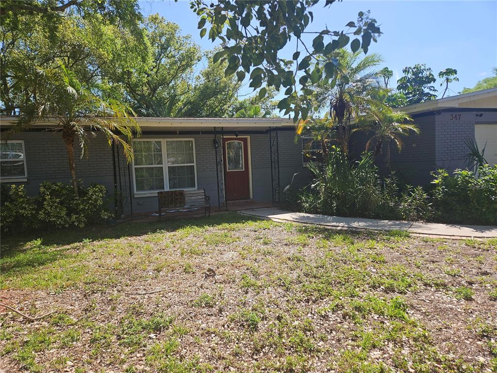 A single-story gray brick house features a red front door and a covered porch — 347 COUNTRY CLUB DRIVE, OLDSMAR, FL