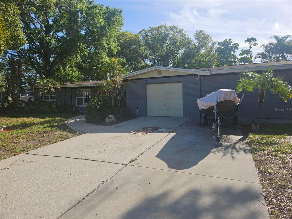 A single-story gray brick house with a garage, a concrete driveway, and a boat trailer — 347 COUNTRY CLUB DRIVE, OLDSMAR, FL