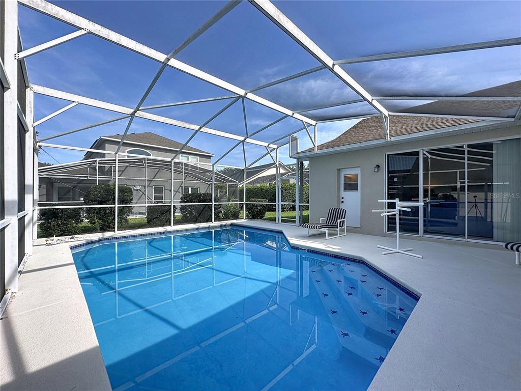 A swimming pool with a blue tiled border is enclosed by a screened-in lanai — 2216 MALLORY CIR, HAINES CITY, FL