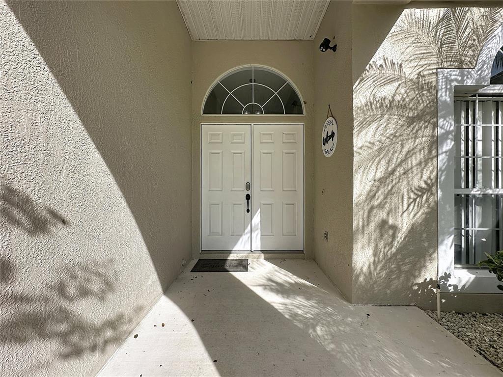 A white double front door with a semi-circular transom window sits under a covered entryway — 2216 MALLORY CIR, HAINES CITY, FL