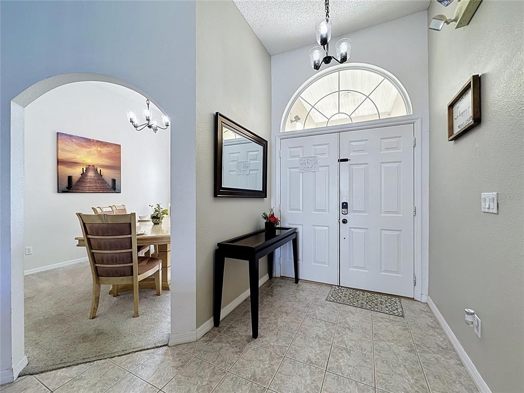 An entryway with tile flooring, a console table, and an arched opening to a dining room — 2216 MALLORY CIR, HAINES CITY, FL