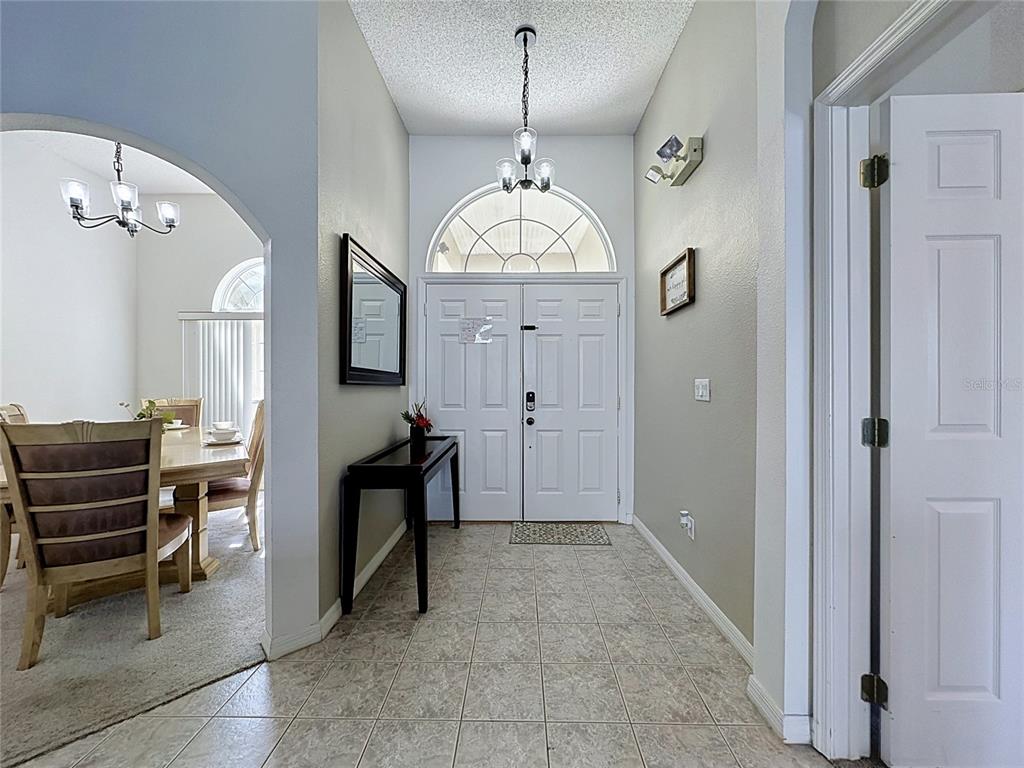 A tiled entryway features a double front door, a console table, and an arched opening — 2216 MALLORY CIR, HAINES CITY, FL