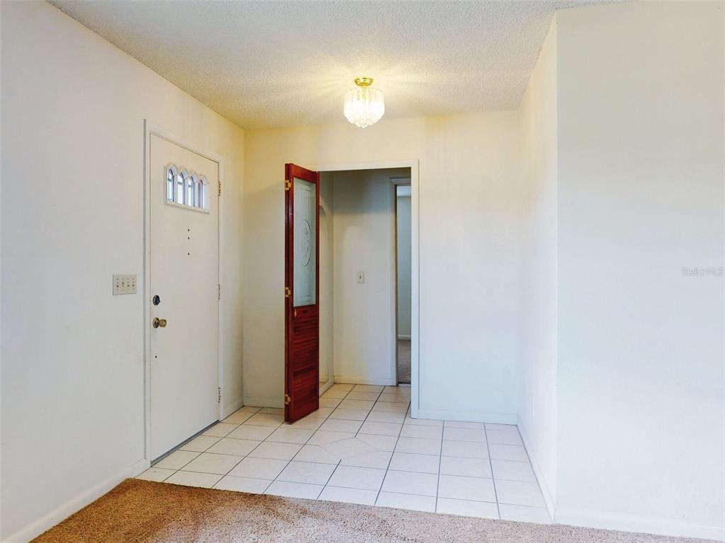 An entryway with white walls, white tile flooring, a front door, and a light fixture — 1362 WOODBINE AVENUE, DELTONA, FL