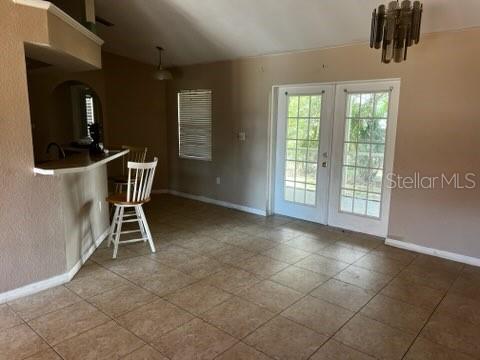 A dining area with tile flooring, a breakfast bar, and glass doors leading outside — 220 PALMETTO CIRCLE NE, PORT CHARLOTTE, FL