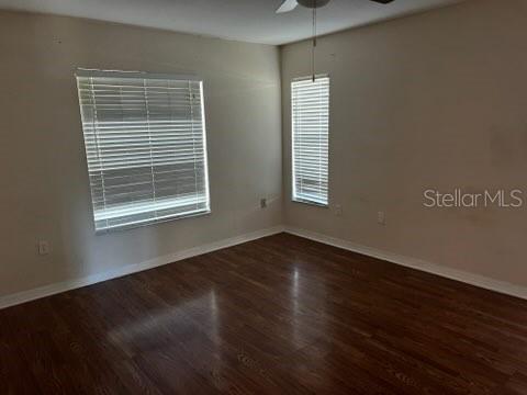 An empty room features wood-look flooring, beige walls, and two windows with white blinds — 220 PALMETTO CIRCLE NE, PORT CHARLOTTE, FL