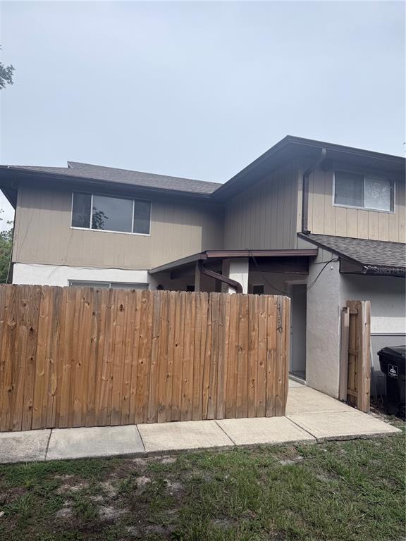 A two-story building exterior features a wooden privacy fence, a concrete patio, and siding — 4530 LIGHTHOUSE CIRCLE UNIT 22, ORLANDO, FL