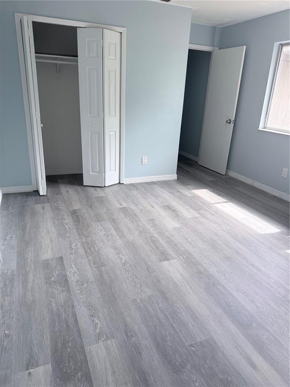 A bedroom with light blue walls, gray wood-look flooring, a closet, and an open doorway — 4530 LIGHTHOUSE CIRCLE UNIT 22, ORLANDO, FL