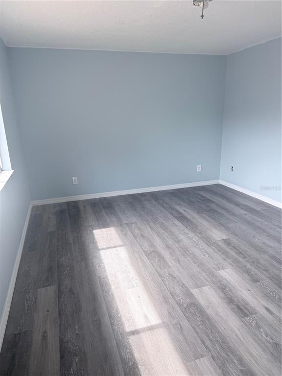 An empty bedroom with light blue walls, gray wood-look flooring, and a ceiling light fixture — 4530 LIGHTHOUSE CIRCLE UNIT 22, ORLANDO, FL