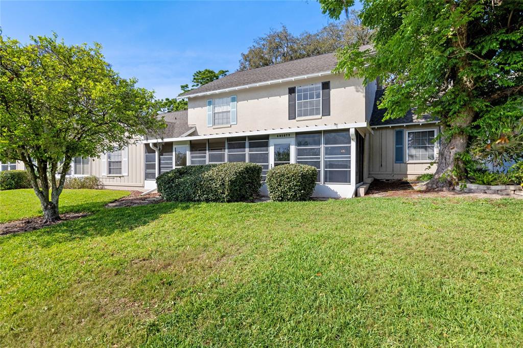 A two-story house with a screened-in porch, tan siding, and a large front lawn — 1337 VILLA LANE UNIT 49, APOPKA, FL