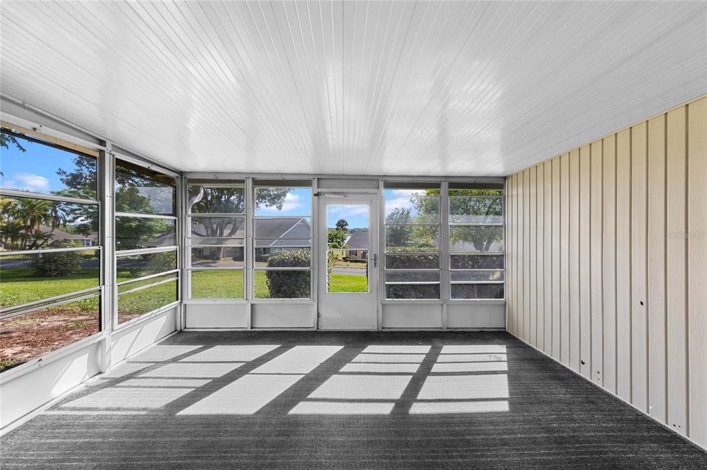 A screened-in porch with a white ceiling, gray carpet, and views of a grassy yard — 1337 VILLA LANE UNIT 49, APOPKA, FL