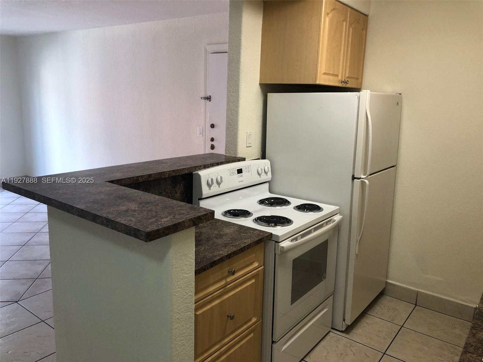 A kitchen features a white stove, a white refrigerator, and a dark laminate countertop — 10744 N Kendall Dr # 16, Miami FL 33176, MIAMI, FL