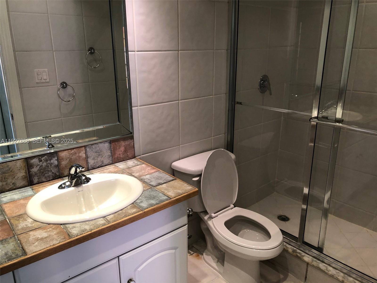 A bathroom features a tiled vanity with an inset sink, a toilet, and a shower — 10744 N Kendall Dr # 16, Miami FL 33176, MIAMI, FL