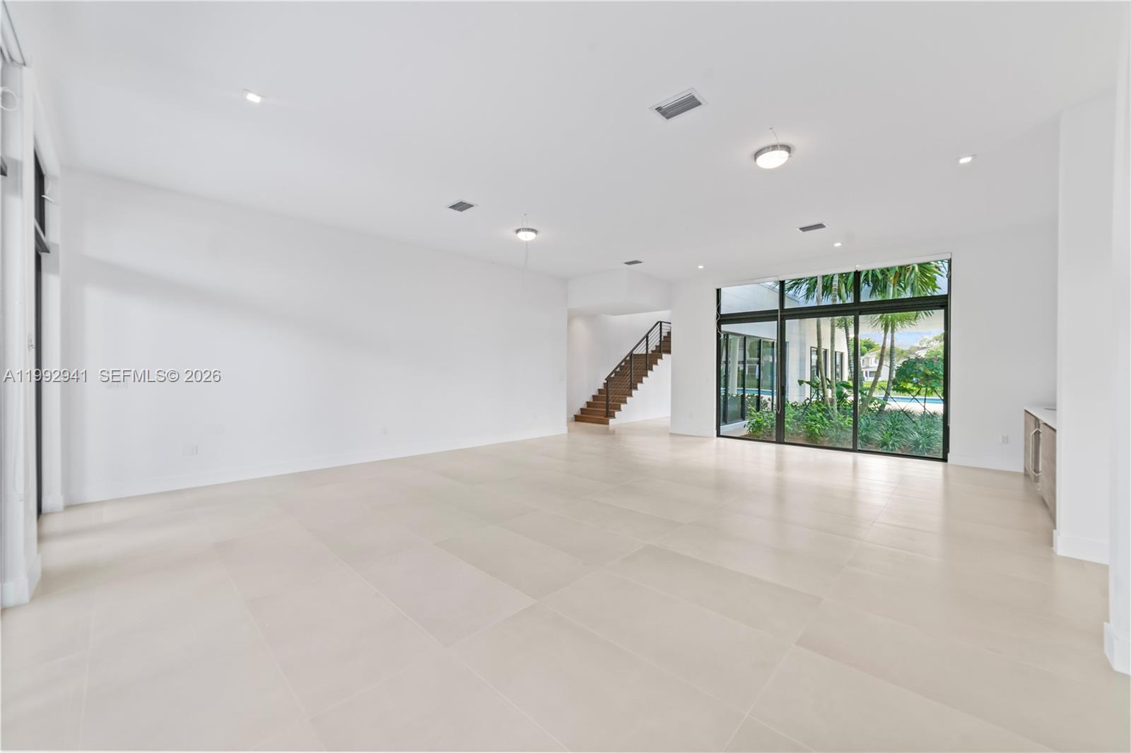 A spacious, minimalist living area features white walls, large floor tiles, and a staircase — 16680 N Botaniko Dr N # 16680, Weston FL 33326, WESTON, FL