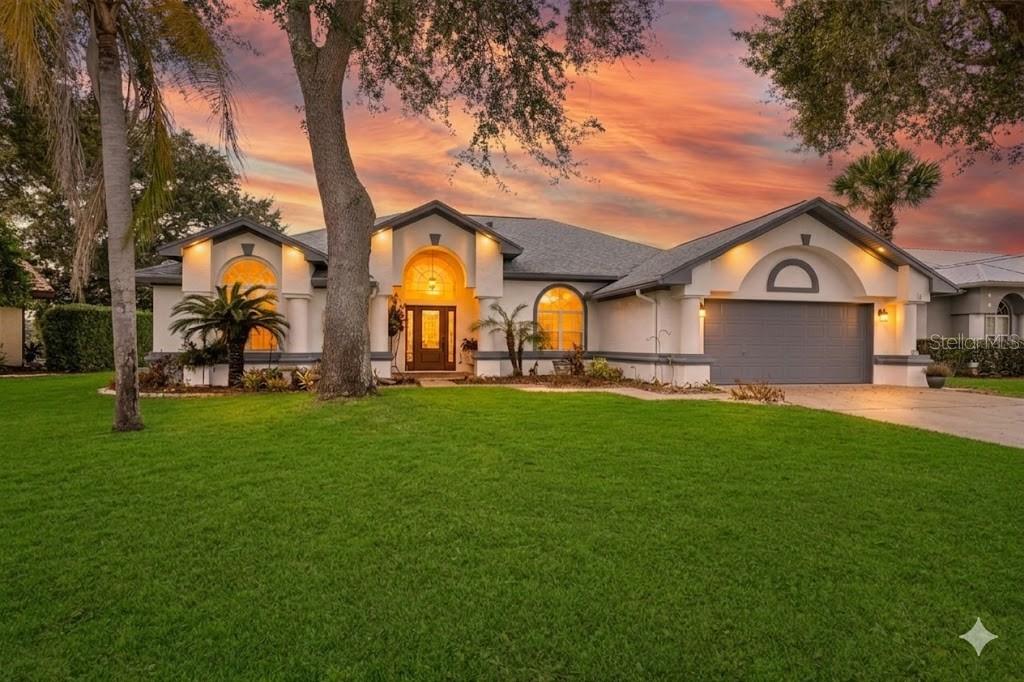A single-story house with a gray garage, arched windows, and a large front lawn — 10 CHELSEA COURT, PALM COAST, FL