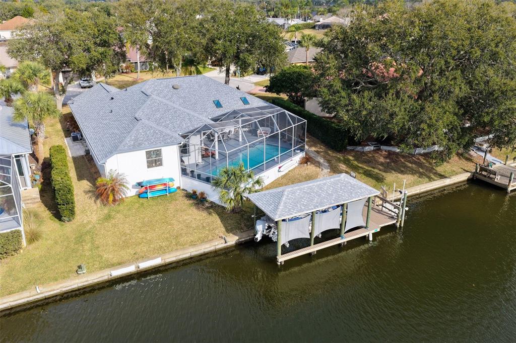 An aerial view shows a waterfront house with a pool enclosure and a boat dock — 10 CHELSEA COURT, PALM COAST, FL